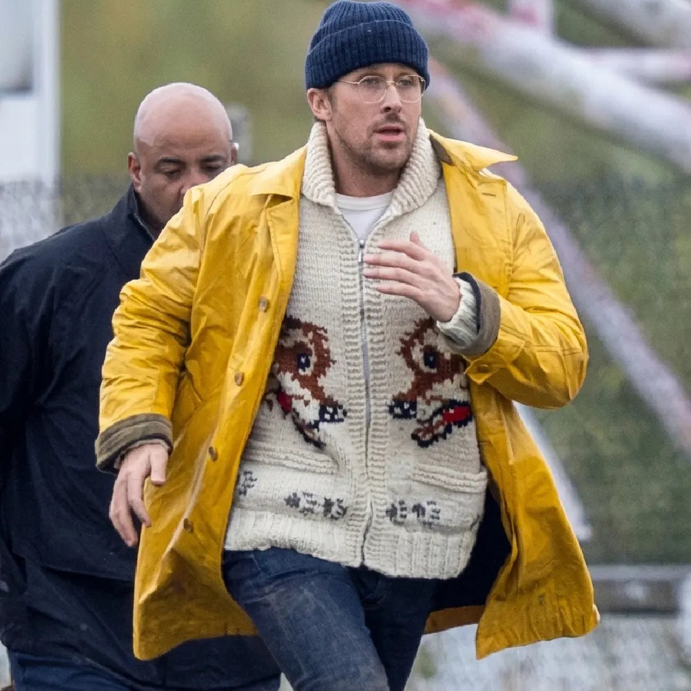 Ryan Gosling wearing the Yellow Coat over a white wolf-patterned knit cardigan and blue beanie.